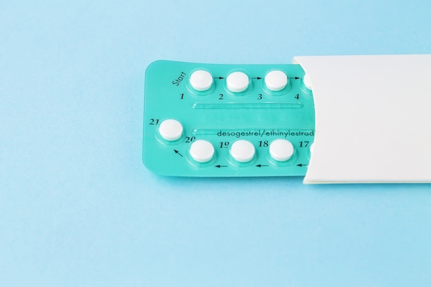 Пакет противозачаточных таблеток с инструкциями. Блистер в белом футляре на синем фоне