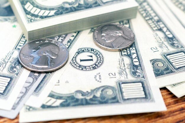 Пачка долларов банкнот и монет крупным планом.