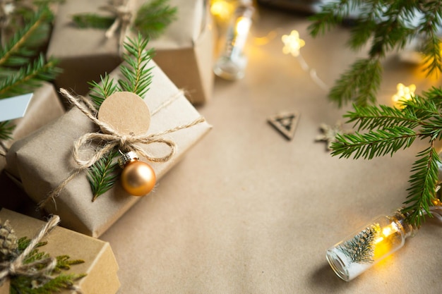 Pack a gift for Christmas and new year in eco-friendly materials: kraft paper, live fir branches, cones, twine. Tags with mock up, natural decor, hand made, DIY. Festive mood. Christmas background