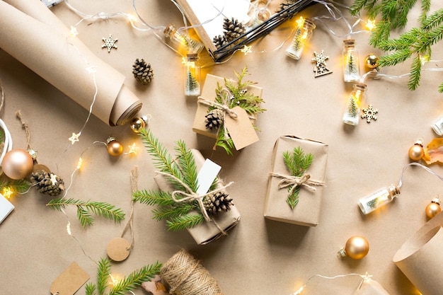 Pack a gift for Christmas and new year in eco-friendly materials: kraft paper, live fir branches, cones, twine. Tags with mock up, natural decor, hand made, DIY. Festive mood. Christmas background