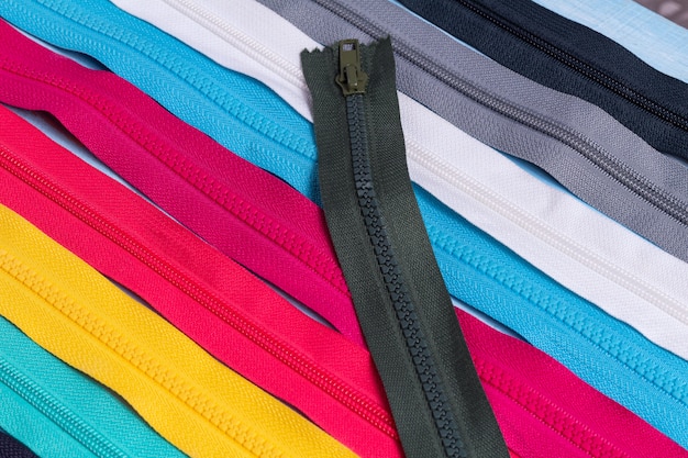 Pack lot of colorful plastic and metal zippers stripes pattern, background close up