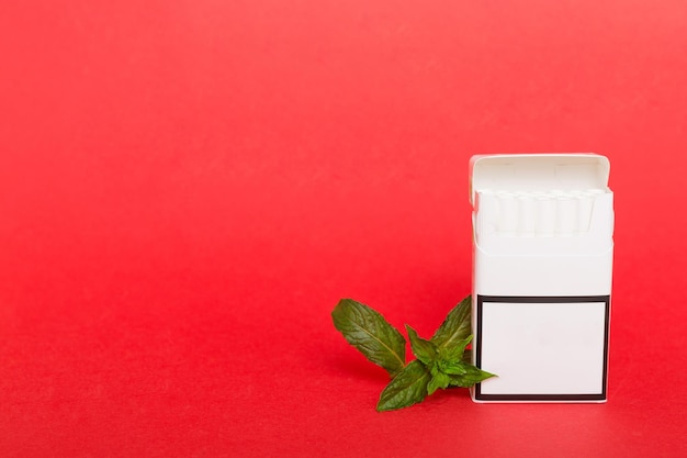 Pack of menthol cigarettes and fresh mint on colored table Menthol cigarettes top view flat lay