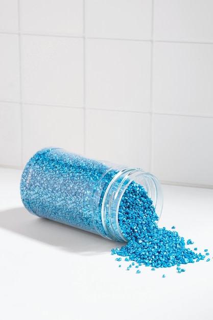 Package of blue shiny crystal salt on the background of the bathroom wall Jar with scattered shimmering blue sea salt Idea of relaxation aromatherapy and self care The effect of sea water on hair