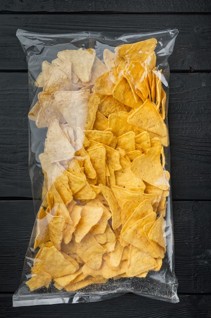 Foto pacchetto tradizionale sacchetto di nachos di mais, sul tavolo di legno nero, vista dall'alto o piatto