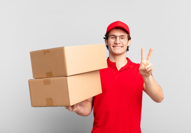 Package deliver boy smiling and looking friendly, showing number two or second with hand forward, counting down