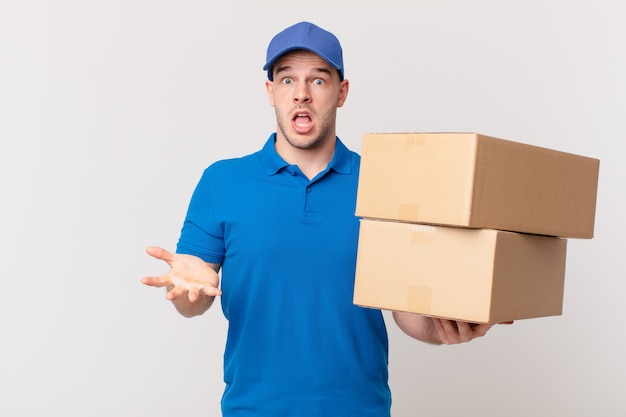 Package deliver man feeling extremely shocked and surprised, anxious and panicking, with a stressed and horrified look