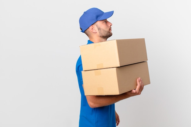 Package deliver man on profile view thinking, imagining or daydreaming