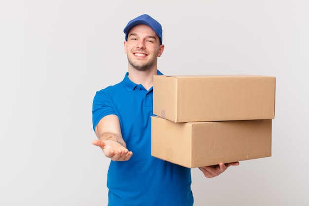 Package deliver man smiling happily with friendly, confident, positive look, offering and showing an object or concept