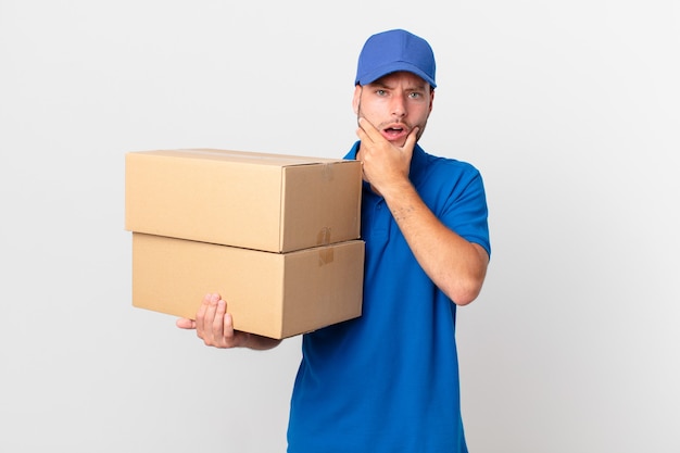 Package deliver man with mouth and eyes wide open and hand on chin