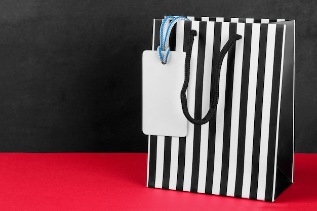 Package for purchases in a strip with a price tag on a red table on a black background with a place for an inscription. concept of black Friday. shopping