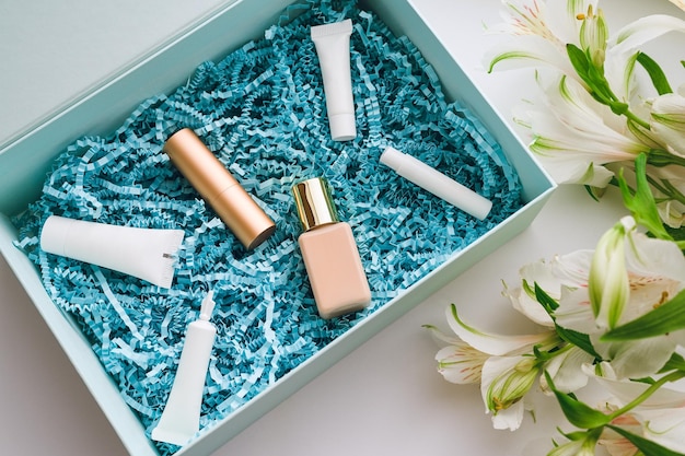 A package with decorative and care cosmetics and perfumes in a blue box and white alstroemerias