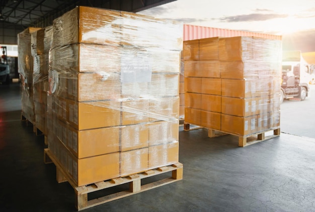 Упаковочные коробки, уложенные в обернутую пластиковую пленку на поддонах на складе Складская логистика
