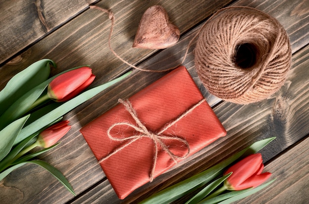 Packed gift box, cord and decorative heart on wooden table