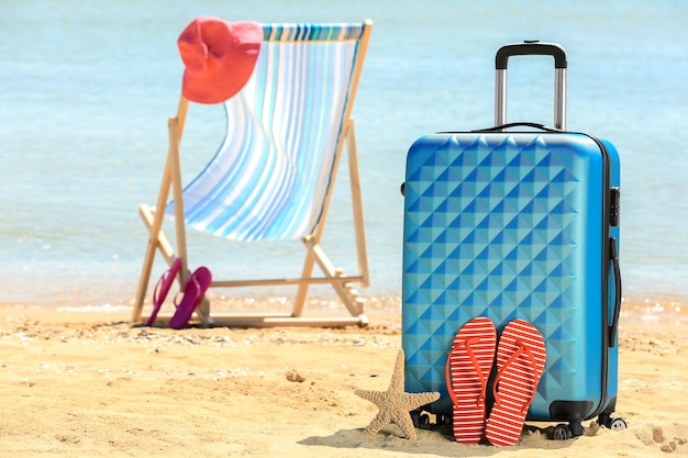 Photo packed suitcase beach chair and accessories at sea shore vacation concept