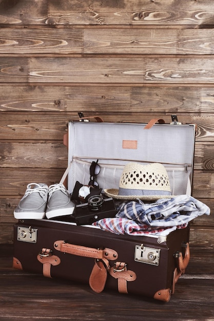 Packed suitcase of vacation items on wooden background