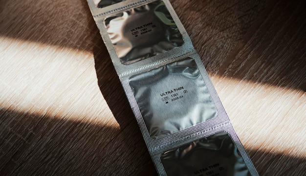 Photo packing condoms on a wooden floor or countertop a ribbon of four condoms in foil packaging