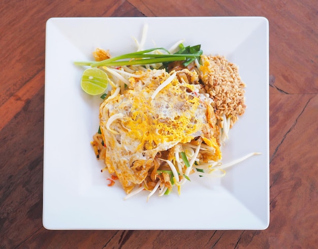 Pad thai food on white plate placed over wooden table