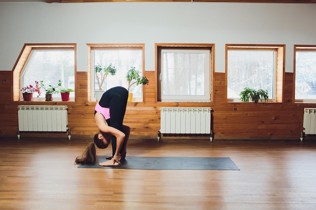 Photo padahastasana beautiful yoga woman practice in a training hall background yoga concept