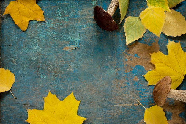 Paddestoelen en herfstbladeren op een houten tafel