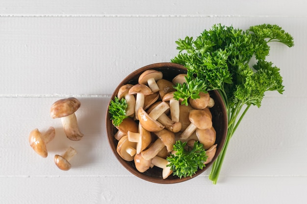 Paddestoelen in een kom van klei en op een witte houten tafel