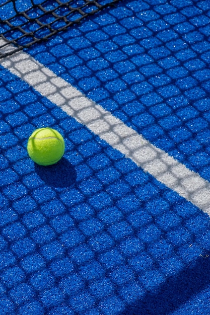 paddle tennis ball in the shade of the net of a blue paddle tennis court racket sports concept