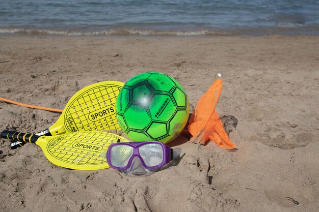 Foto racchetta da paddle tennis e palla di colore giallo e spiaggia che gioca a palla sulla spiaggia copia spazio