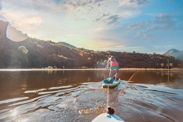 Foto paddleboarding in un paesaggio fluviale sereno con gentili raggi dell'alba