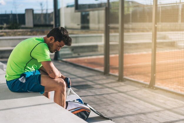 Foto giocatore di padel che si siede sul riposo del pavimento