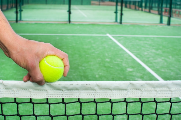 Padel tennis court and hand with ball