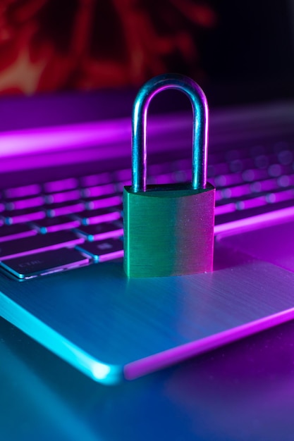 A padlock sits on a laptop keyboard with a purple and blue light behind it.