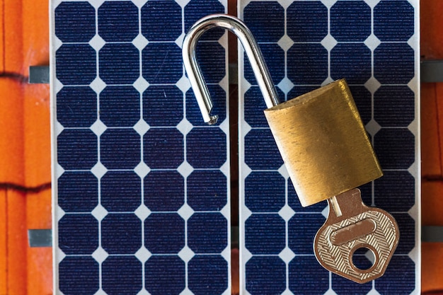 Padlock with key on photovoltaic solar panel on black 