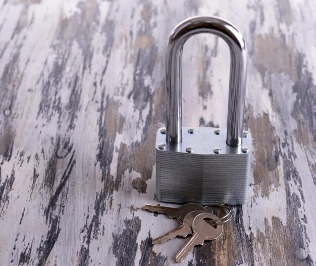 Padlock with keys on wooden background