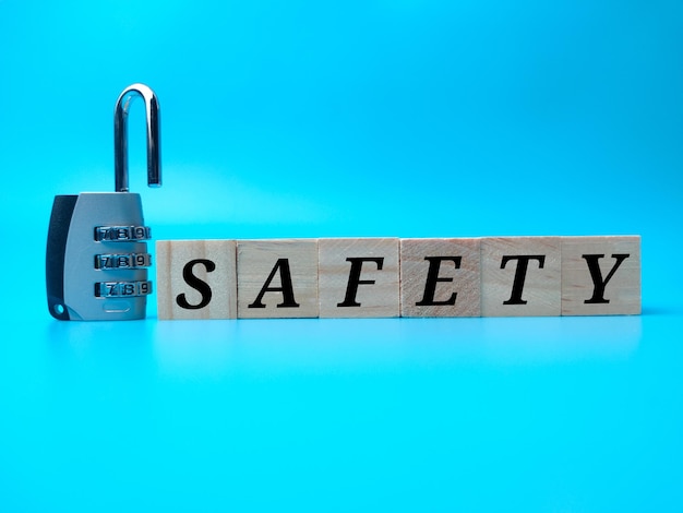 Padlock and wooden cube with word SAFETY on a blue background