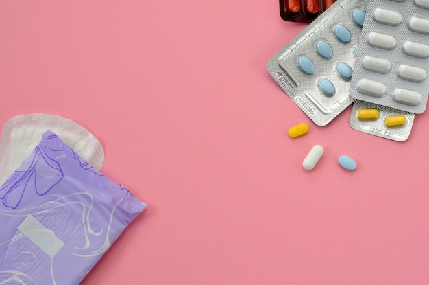 Pads and pills on a pink background flat lay