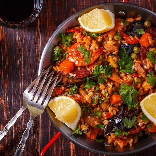 Paella with chicken, chorizo, seafood, vegetables and saffron served in the traditional pan.