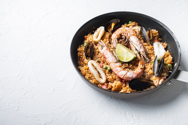 Paella with seafood and chicken on white background with space for text