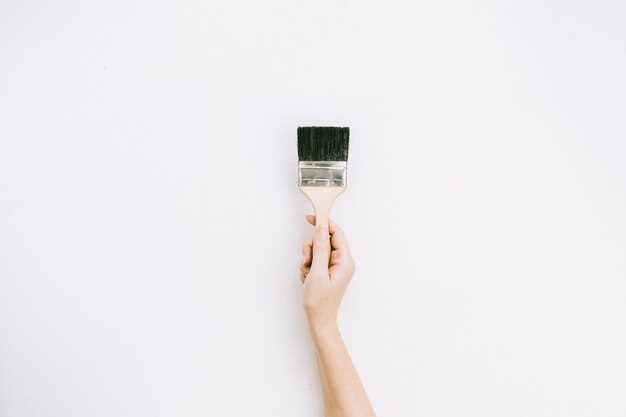 Pain brush on female hand on white background. Flat lay, top view