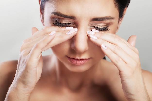 Pain in the eyes. Young beautiful woman holds her hand in front of her eyes. Strong pain. The concept of health. 