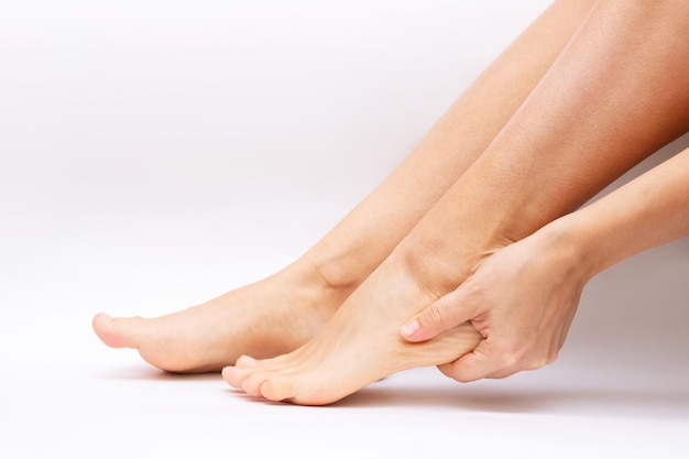 Pain in the foot from uncomfortable shoes a woman holds a sore\
heel dry feet