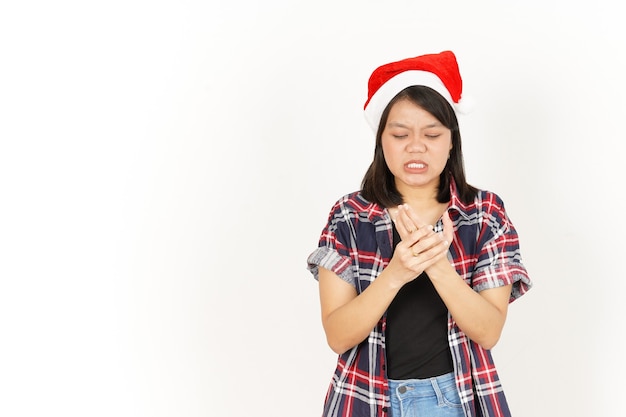 Боль на руке красивой азиатской женщины, носящей красную клетчатую рубашку и шляпу Санта-Клауса, изолированную на белом