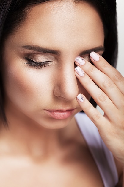 Pain. Portrait of a beautiful young brunette with a bare shoulder, feels great headache, health problems, migraine, professional makeup.