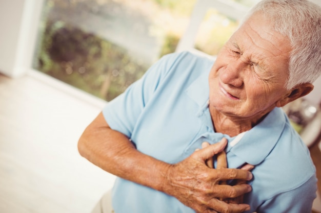 Painful senior man with pain on heart at home