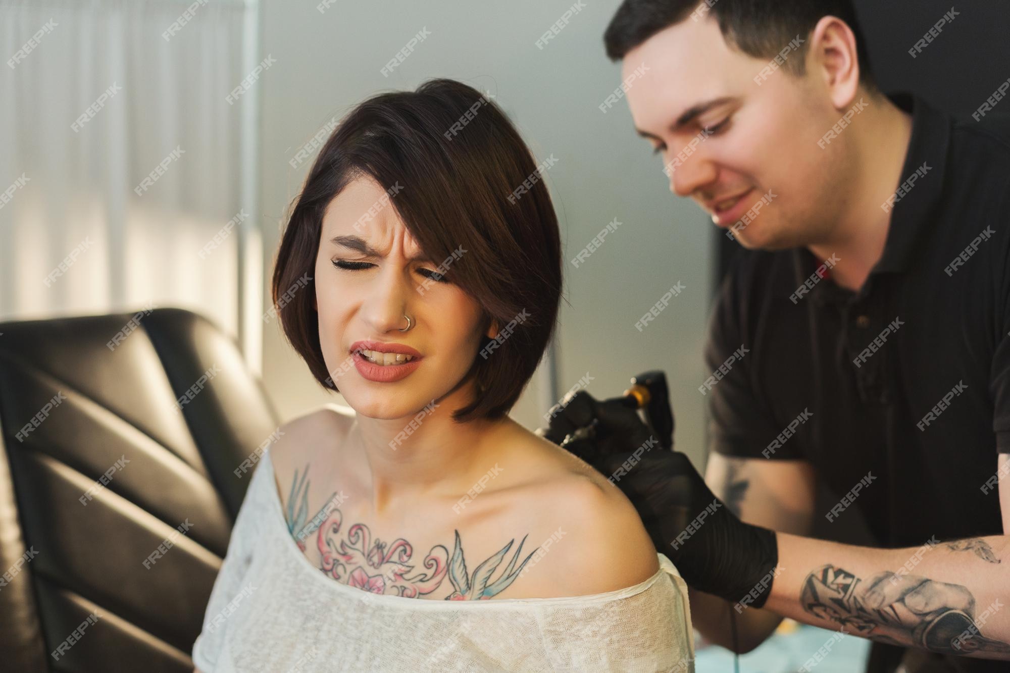 Premium Photo | Painful tattooing process, young woman grimacing while  master making tattoo on her back. popular body modification, modern  lifestyle, copy space