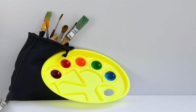 A paint brush case with a yellow cover and a black canvas bag with paint brushes inside.