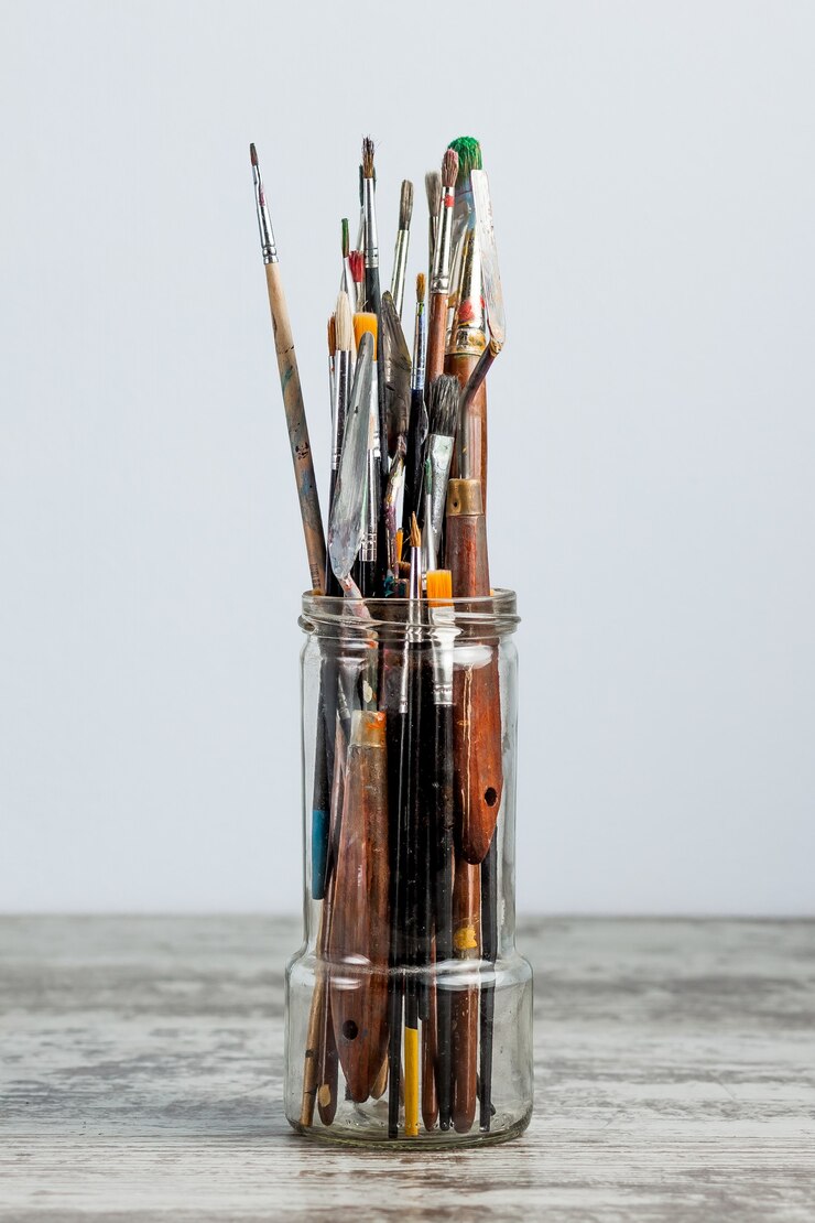 Photo paint brush in a glass, jar. on a light blue surface. with copy space