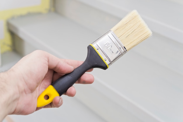 Paint brush in hand, applying paint to a wooden surface during repair