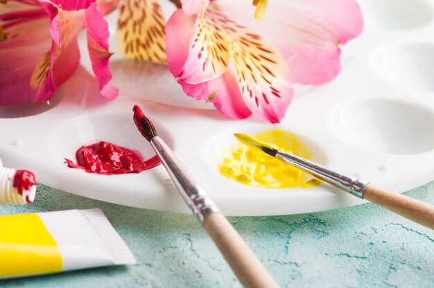 Paint brush, red, yellow watercolor paint with spring flowers