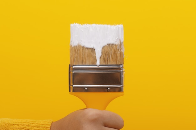 Paint brush with white paint in hand