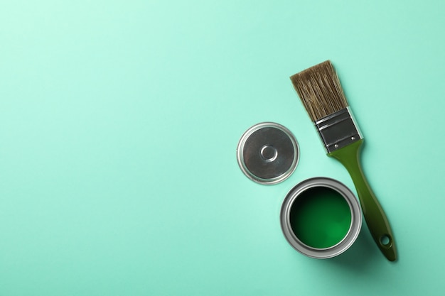 Paint can and brush on green background, top view