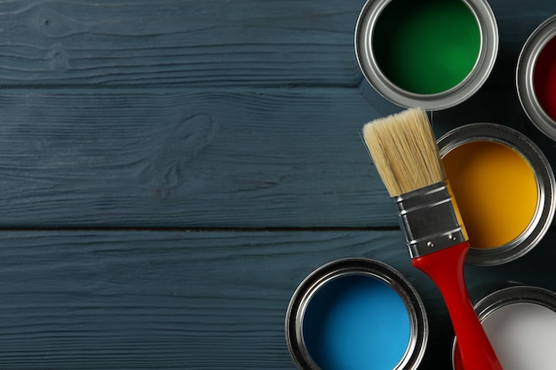 Paint cans and brush on wooden surface